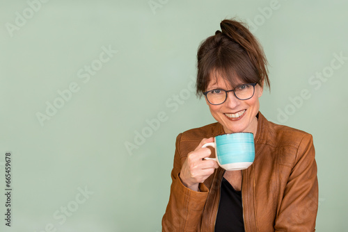 Portrait hübsche Frau mit mit Brille langen Haaren, trinkt Kaffee photo