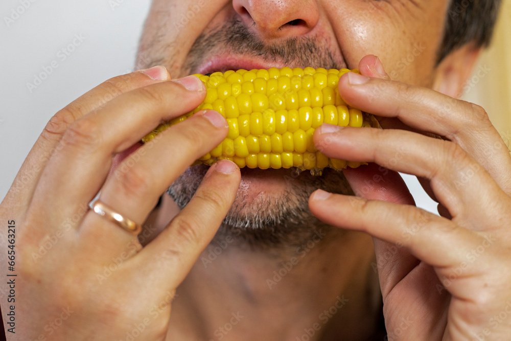man bites off a piece of sweet corn with his teeth man bites off a piece of sweet corn with his teeth