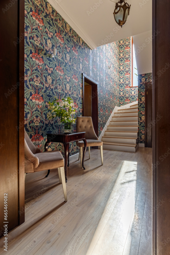 A coffee table with a bouquet and a cup, standing near the stairs to the second floor A coffee table with a bouquet and a cup, standing near the stairs to the second floor