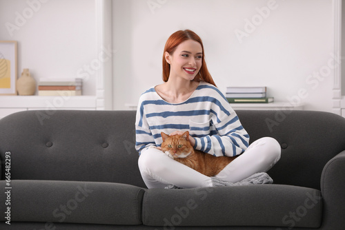 Happy woman with her cute cat on sofa at home