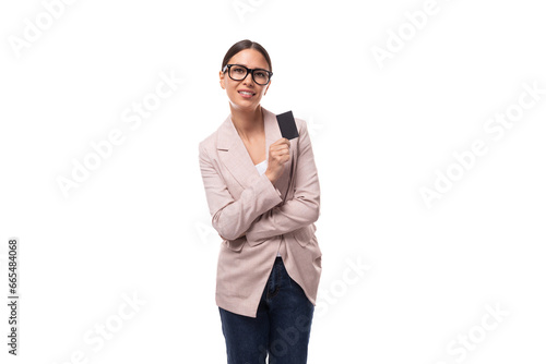 young friendly slender european brunette woman shows a plastic card with a mockup on a white background