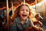Happy young girl enjoy while playing on a colorful carousel, having fun at an amusement park. Children day.