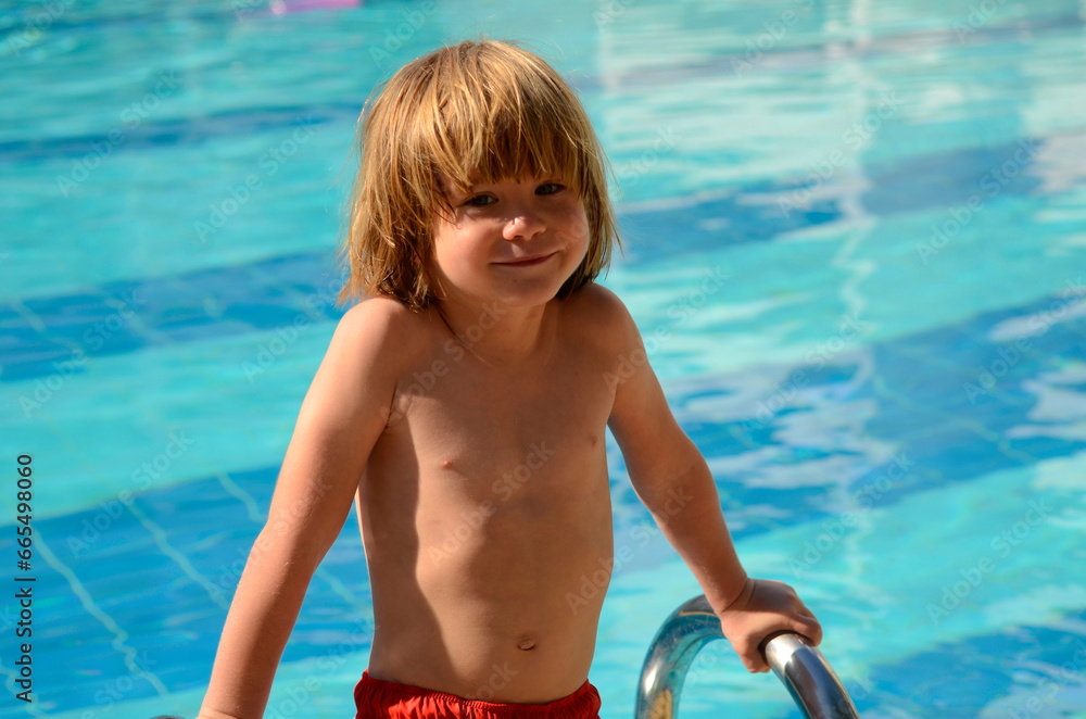 Cute boy learning to swim in the pool. Splashes, emotions, swimsuit. Family holiday at the resort, children on a trip. Summer holidays