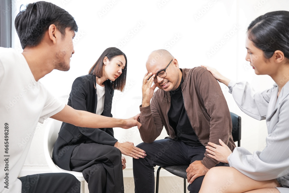 Group of Diverse asian people supporting desperate unhappy man. Depressed male patient suffering from bullying, sharing personal problems at psychological therapy group meeting. Group of Diverse asian people supporting desperate unhappy man. Depressed male patient suffering from bullying, sharing personal problems at psychological therapy group meeting.