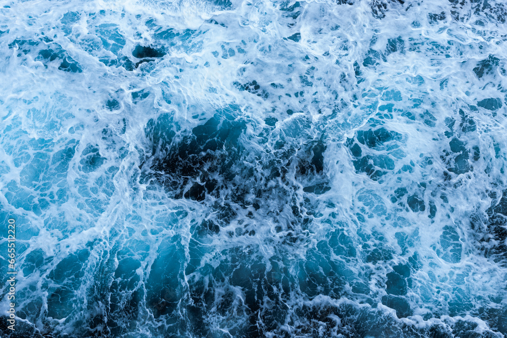 Fototapeta premium High angle view of a blue abstract background with sea foam design. Drone pointing view