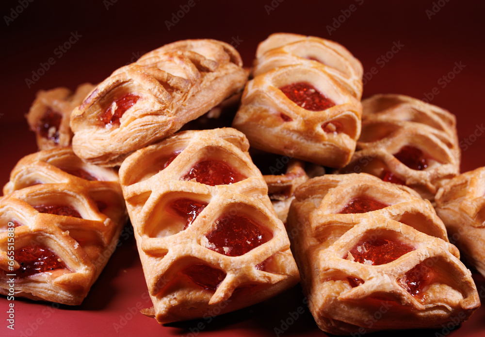 Puff pastry pastry with lingonberry jam on a dark red background. Cookies with lingonberry jam. Puff pastry pastry with lingonberry jam on a dark red background. Cookies with lingonberry jam.