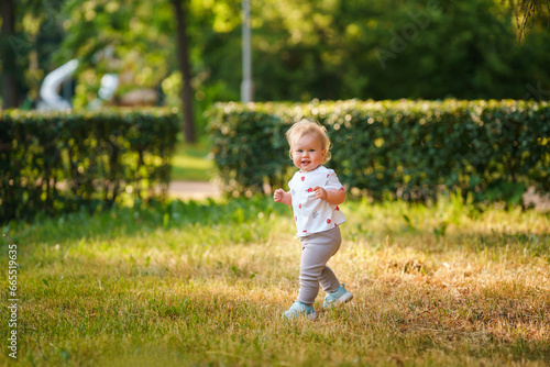 Caucasian little child baby in the park in summer in the setting sun, outdoor walking