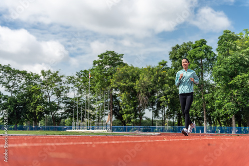 Young Asian women are exercising with outdoor running with a running track background in the morning. Concept healthy running and outdoor exercise,Tracking shot,