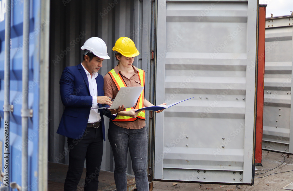 Two Young Engineers standing in the shipping yard tracking the cargo inventory and checking container box for safety. Two Young Engineers standing in the shipping yard tracking the cargo inventory and checking container box for safety.