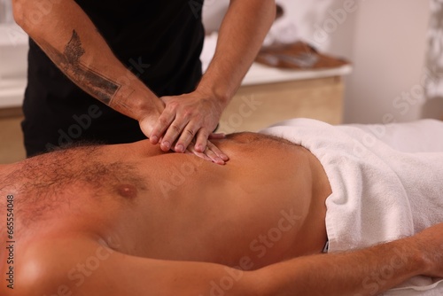 Man receiving professional belly massage in spa salon  closeup