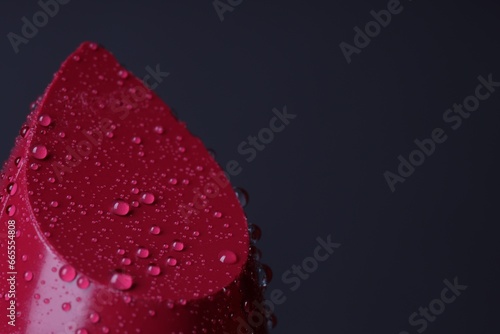 Red lipstick with water drops on dark gray background, macro view. Space for text