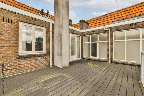 an outside area with wood flooring and brick buildings in the background, there are two windows on each side © Casa imágenes