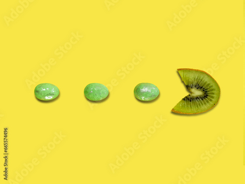 Creative layout made of kiwi fruit eating green Easter eggs against yellow background. Original lemon decoration. Fruit concept. Minimal summer design. Creative Easter idea.