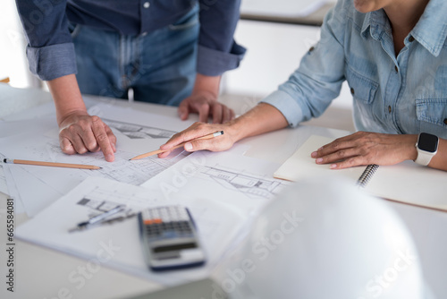 Two engineer architect discussion and inspecting sketching about interior architectural building on blueprint to analysis technical for construction plan while working together in workplace site
