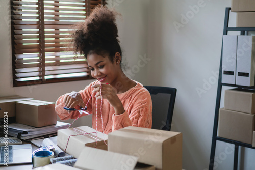 African american women use scissor to cutting rope while tying parcel box to preparing delivery