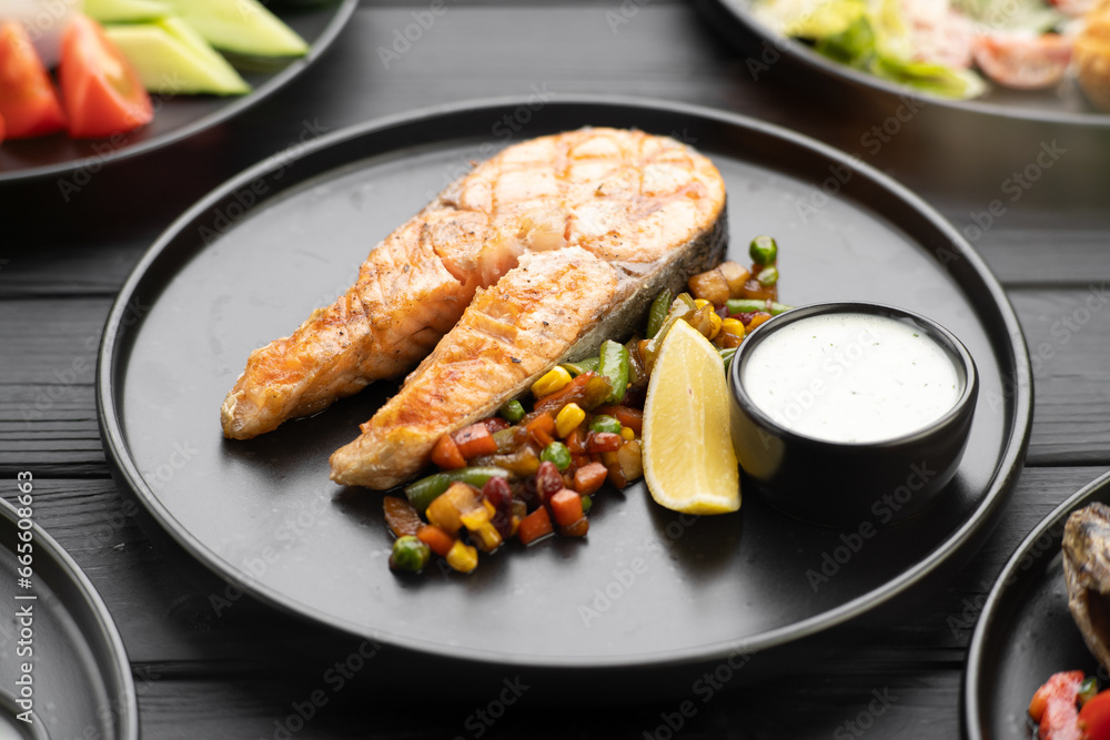 Grilled salmon fish steak with vegetables on black plate. Keto diet concept. Grilled salmon fish steak with vegetables on black plate. Keto diet concept.
