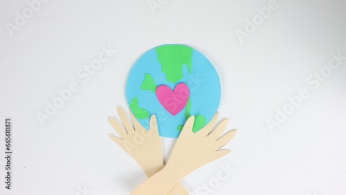 Green globe planet eco concept. Earth day postcard close up. Stop motion paper animation. Pink heart beating. Ecology concept. Hands hold love sign. People show hug gesture. Whole world art card.