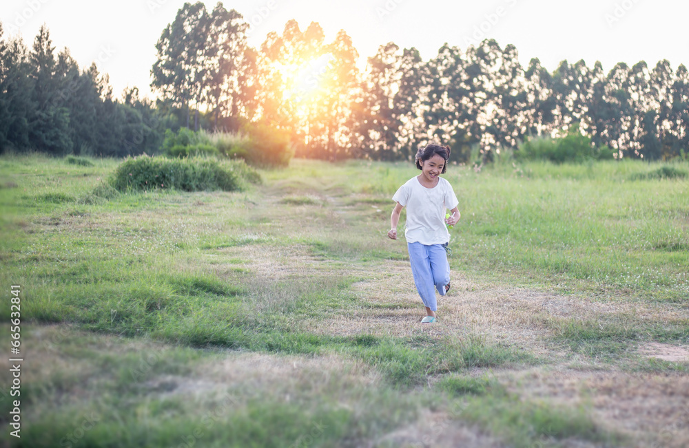 Little girl running on meadow with sunset.
