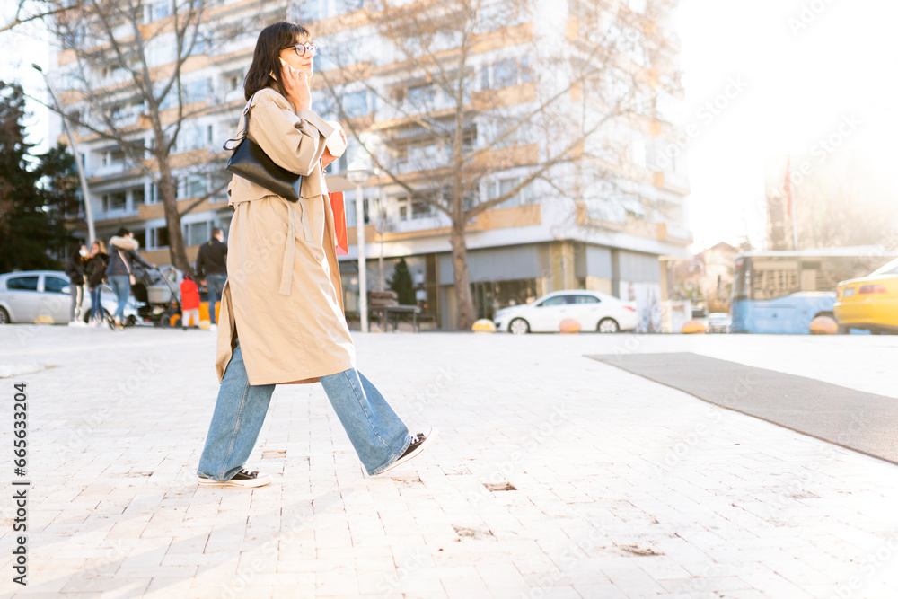 young woman in casual clothing walking back to home talking on phone. young businesswoman using cellphone on city street with urban background.