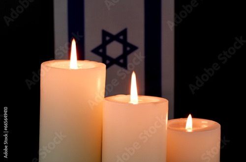 Israel flag and burning candles on black background. Memorial and pray concept. 