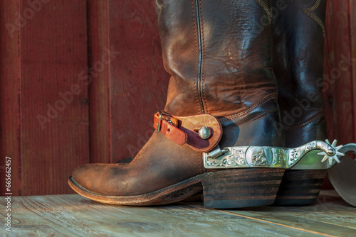 Old brown cowboy boots with spurs on a wood surface in sunlight photo