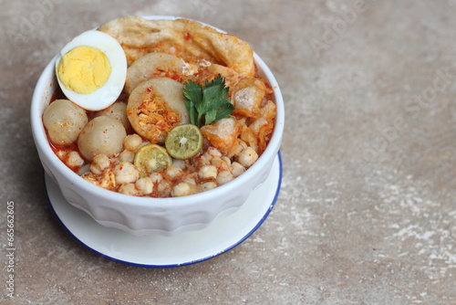 Meatball chicken soup or baso aci with egg and lime topping in white bowl from Bandung , West Java Indonesia. photo