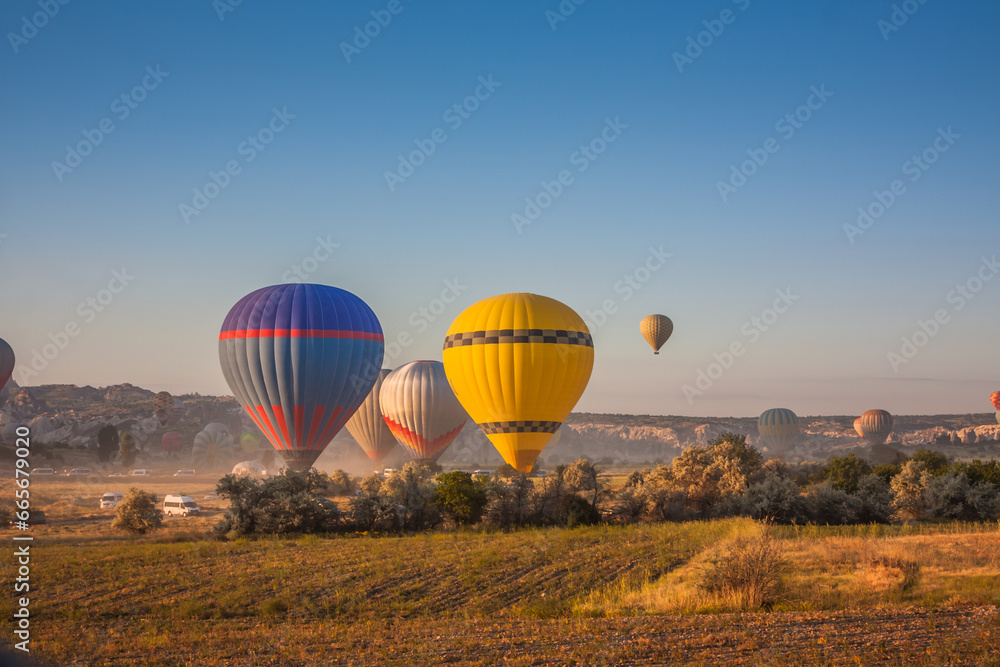 Obraz premium Hot air balloons take off from the ground early in the morning. Hot air balloons flying over bizarre rock landscape in Cappadocia. Beautiful hot air balloons in the morning sky. Goreme. Turkey