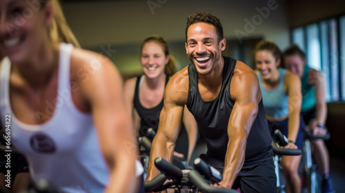Portrait of smiling man on exercise bike with friends  in gym photo