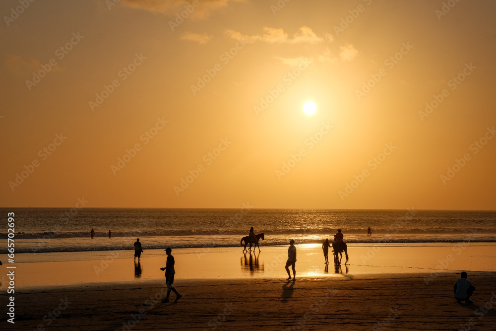 A Beach Abuzz with Life, Bathed in the Glow of Kuta's Orange Twilight