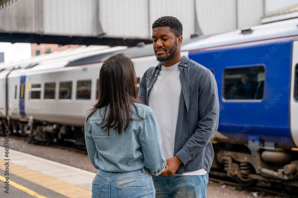 Happy young couple awaiting train at railway station platform Happy young couple awaiting train at railway station platform