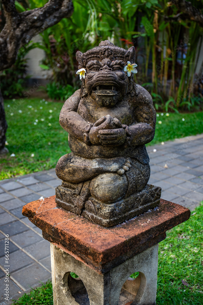 Park area with tropical plants and traditional statues of the Hindu faith and for decoration. Tropical island life as a tourist in Bali Indonesia