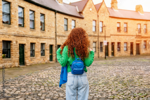 Young woman with red curly hair exploring old euroean town photo