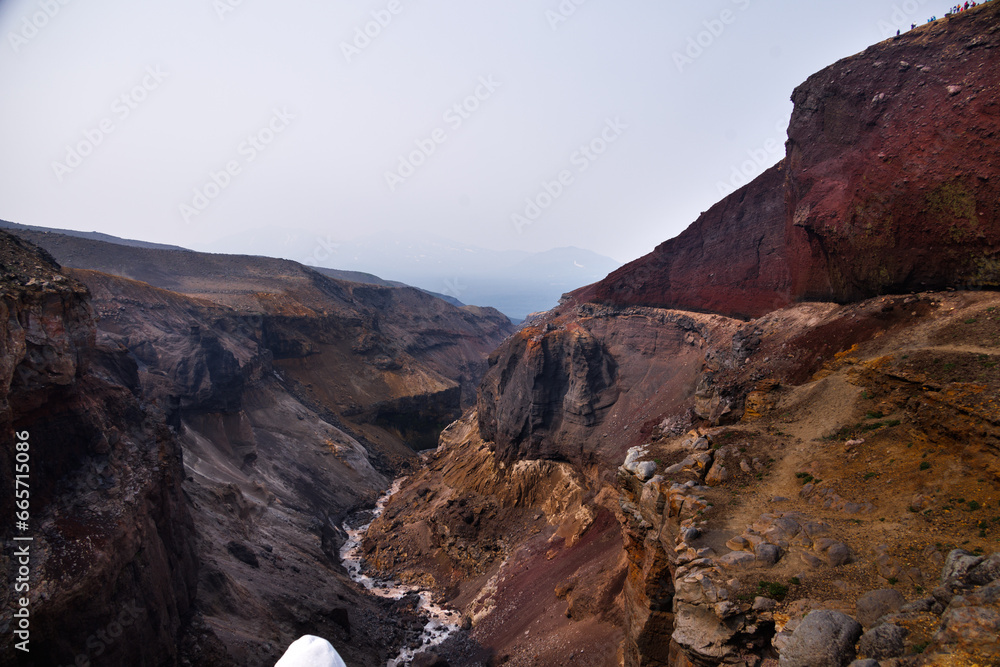 Obraz premium Beautiful landscape of Kamchatka Peninsula: view of Dangerous Canyon , picturesque waterfall on the river Vulkannaya under the active Mutnovsky Volcano.