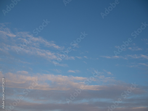 Blue sky after rain,. Beautiful Cumulus clouds flying across the sky, sunset rays, pink shades in the clouds, deep blue sky