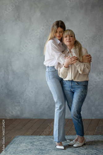 Mom and adult daughter, family portrait, two generations of women. Portrait in the studio in bright colors © Ulia Koltyrina