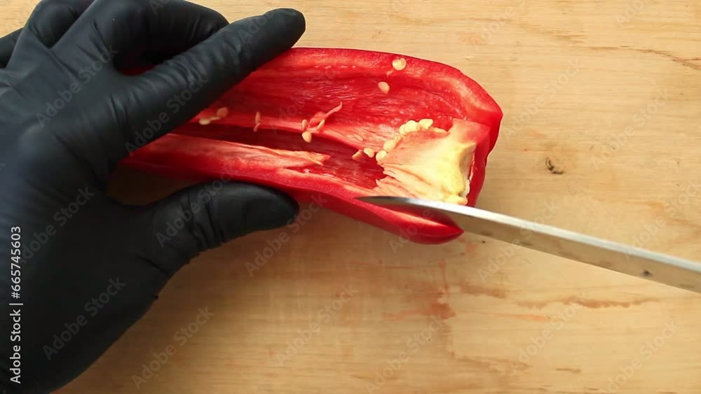 The cook cuts fresh red sweet pepper with a knife on a wooden board. Concept of catering, cooking. The cook cuts fresh red sweet pepper with a knife on a wooden board. Concept of catering, cooking.