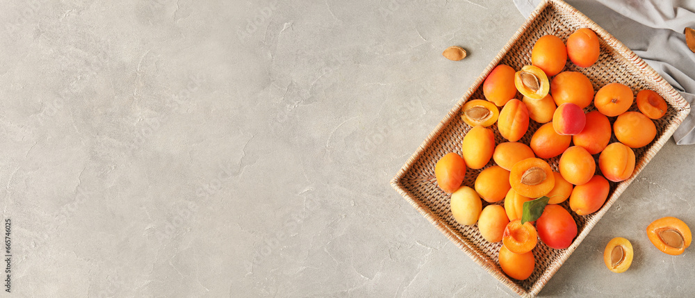 Wicker box of sweet apricots on grey background with space for text, top view
