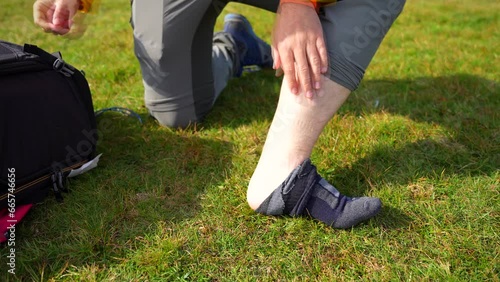 Detail shot of a guy peeling off a hiking sock on the grass. Slow motion photo