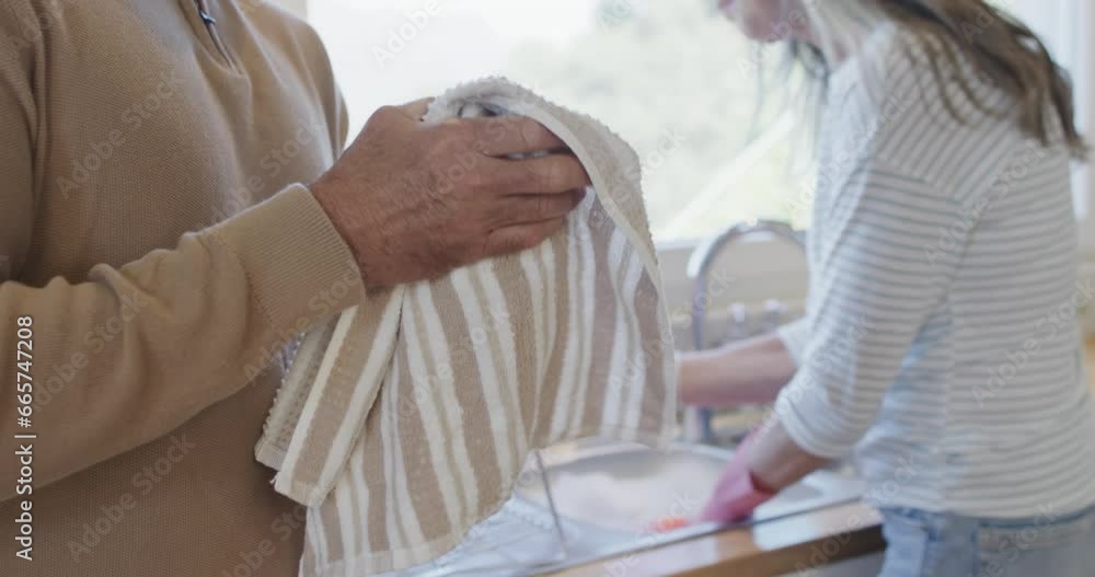 Middle aged caucasian couple washing dishes in kitchen at home, slow motion Middle aged caucasian couple washing dishes in kitchen at home, slow motion