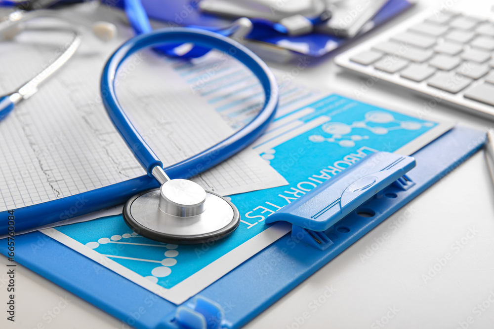 Stethoscope with cardiogram and laboratory test on white medical desk, closeup