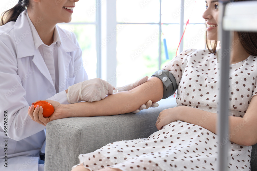 Female doctor taking young donor's blood in clinic Female doctor taking young donor's blood in clinic
