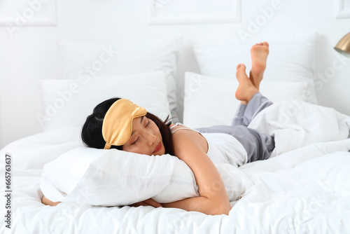 Beautiful Asian woman with sleeping mask in bedroom