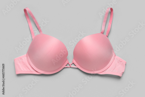 Pink female bra on grey background