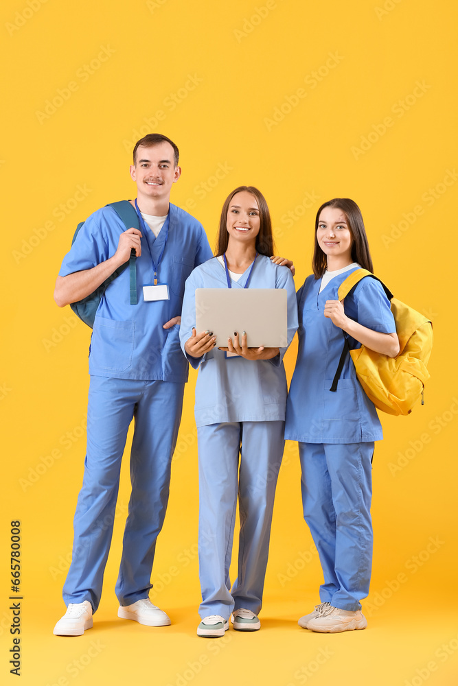 Group of medical students with laptop on yellow background