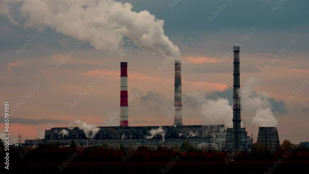 Smoking chimneys of a coal power plant at sunset. Industrial landscape of a plant polluting the environment and atmosphere. Environmental pollution and global warming concept. Smoking chimneys of a coal power plant at sunset. Industrial landscape of a plant polluting the environment and atmosphere. Environmental pollution and global warming concept.