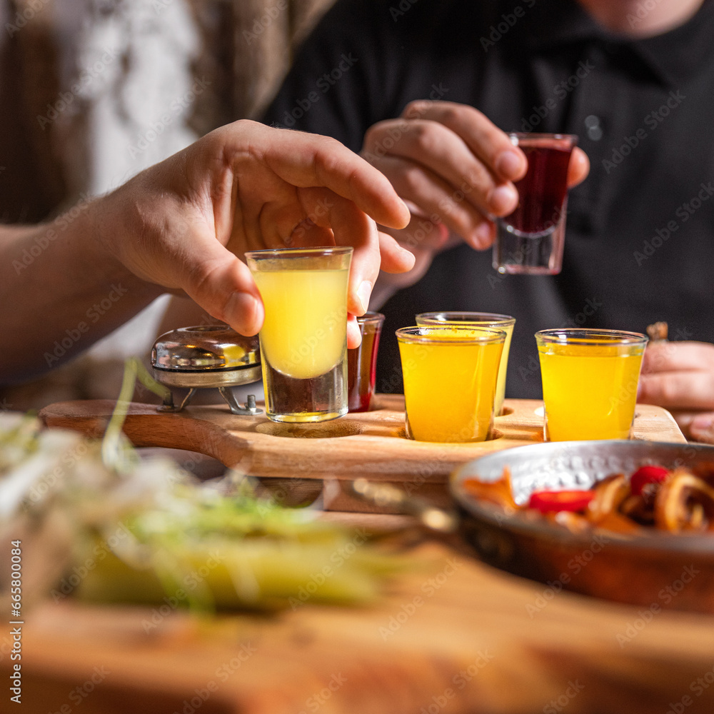 Close-up of male hands cheers with glasses of vodka and liqueur. People drinking at aperitif. Party and toast concept Close-up of male hands cheers with glasses of vodka and liqueur. People drinking at aperitif. Party and toast concept
