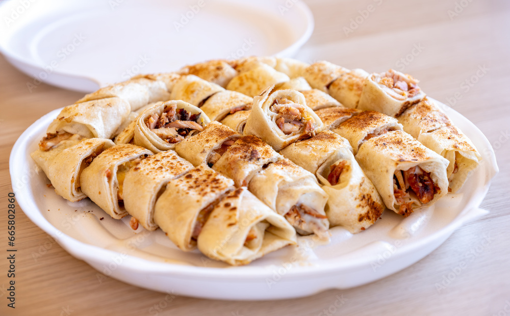 Pieces of shawarma on wooden table with dips and arranged on white plate Pieces of shawarma on wooden table with dips and arranged on white plate