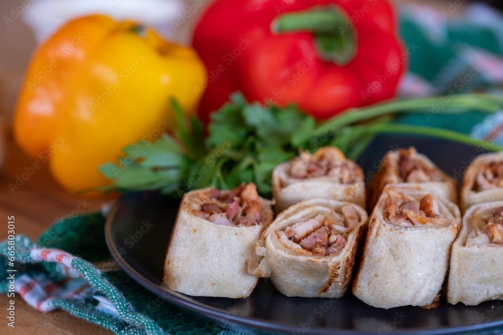 Shawarma pieces on wooden table with sweet peppers in the background and knife Shawarma pieces on wooden table with sweet peppers in the background and knife