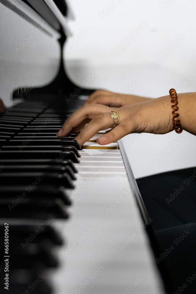 Fototapeta premium Middle Eastern female hands playing piano in conservatory