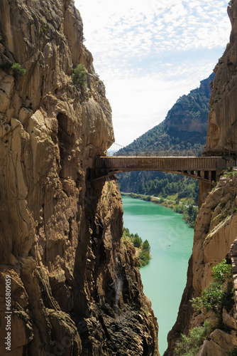 View of wooden bridge by cliffs and lake in El camito del Rey